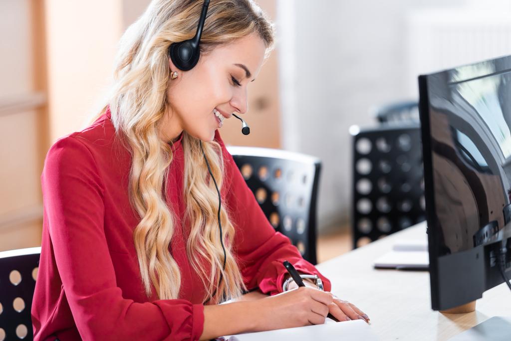 Seitenansicht der schönen Callcenter-Betreiberin im Headset am Arbeitsplatz im Büro - Foto, Bild