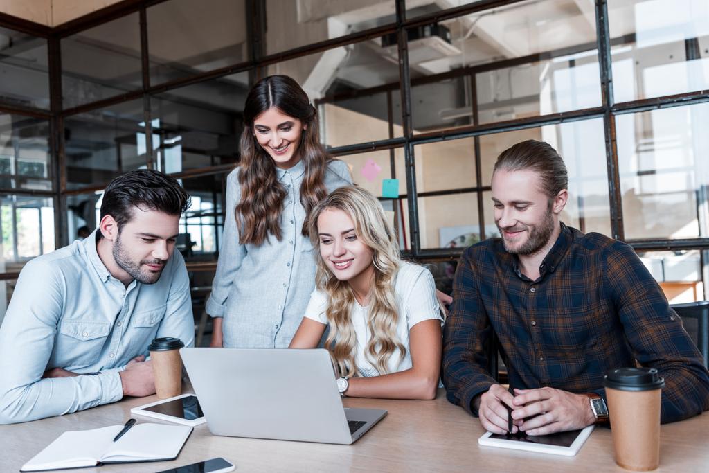 jovens empresários sorridentes que trabalham com laptop no local de trabalho
 - Foto, Imagem