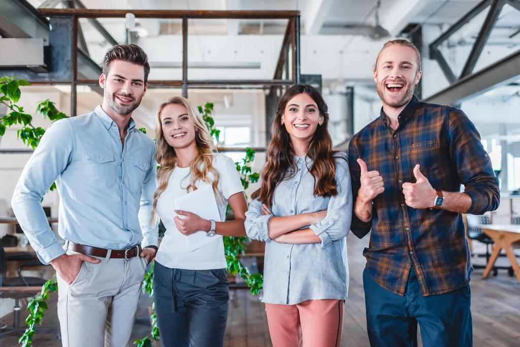 happy young business team showing thumbs up and smiling at camera in office - Photo, Image