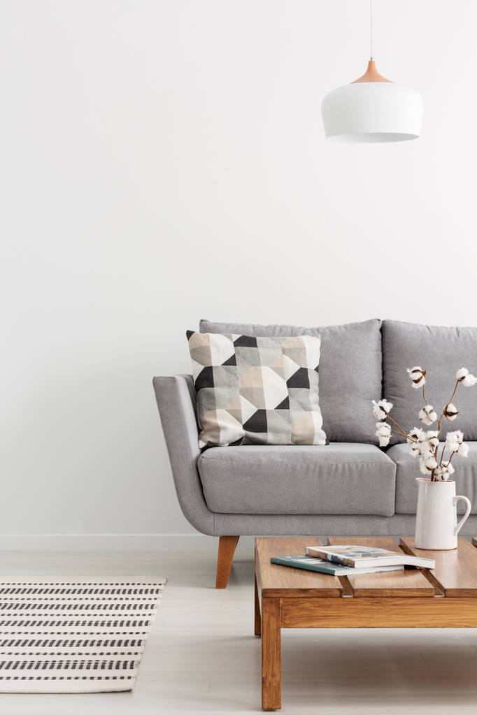 Κάθετη προβολή απλό σαλόνι με ξύλινο τραπεζάκι του καφέ και γκρι καναπέ με διαμορφωμένο μαξιλάρι - Φωτογραφία, εικόνα