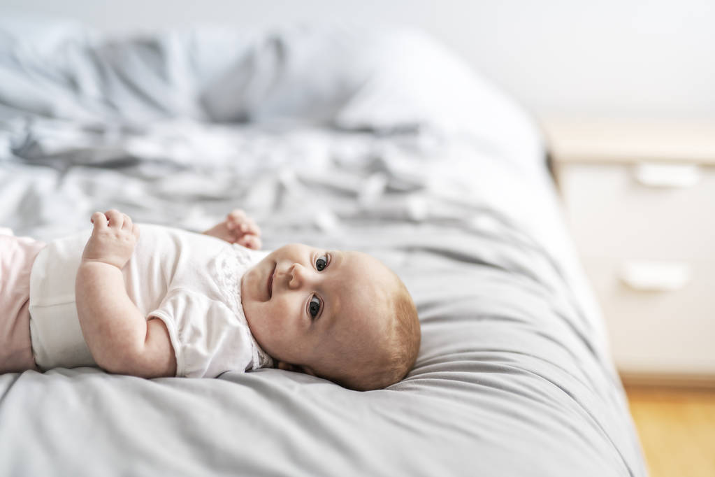 Imádnivaló két hónapos kislány pihentető hálószobában kötött takaró egy napsütéses reggelen - Fotó, kép