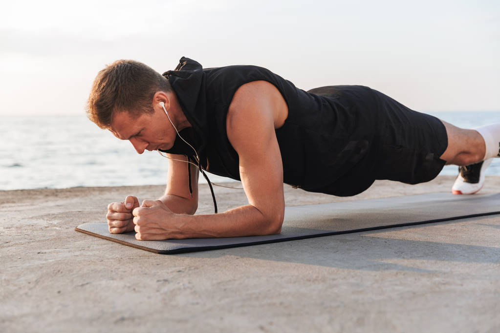 Foto ze silných mladého sportovce venku na pláži se sportovní cvičení. - Fotografie, Obrázek