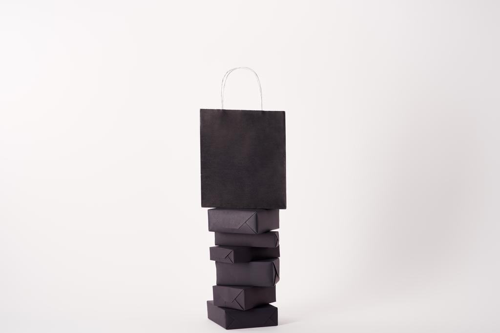 bolso de compras negro en cajas apiladas en superficie blanca, concepto de viernes negro
 - Foto, imagen