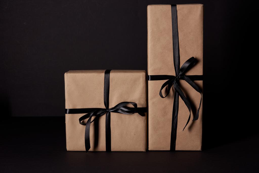 wrapped gift boxes with bows on black surface, black friday concept - Photo, Image