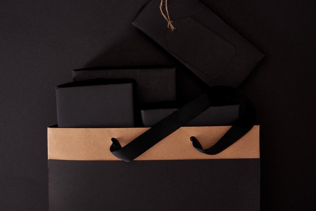 верхний вид черных ящиков в сумке на черной поверхности, черная пятница концепции
 - Фото, изображение
