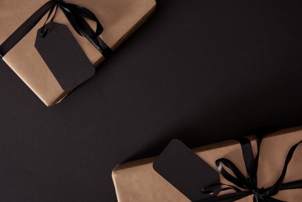 üstten görünüm Craft hediyeler siyah etiketleri ile siyah yüzey, siyah Cuma konsepti üzerine sarılmış. - Fotoğraf, Görsel