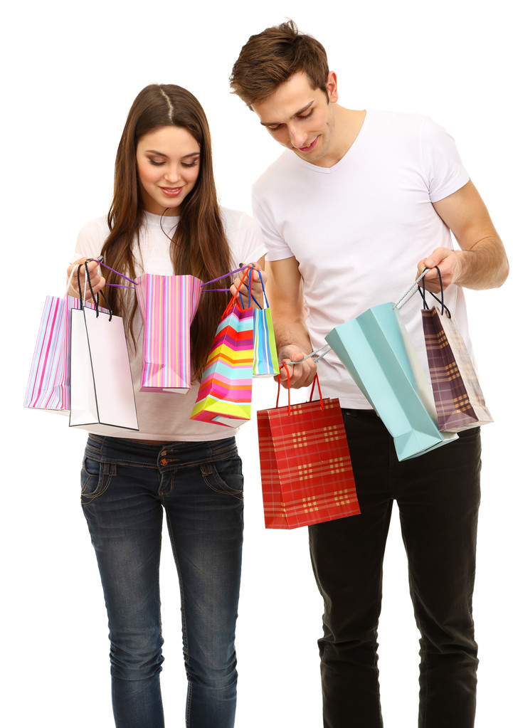 νεαρό ζευγάρι ψώνια και κρατώντας πολλές τσάντες αγορών που απομονώνονται σε λευκό - Φωτογραφία, εικόνα