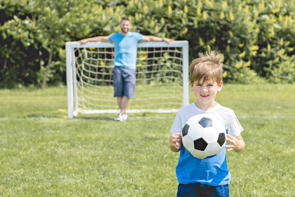 Чоловік з дитиною грає у футбол зовні на полі
 - Фото, зображення