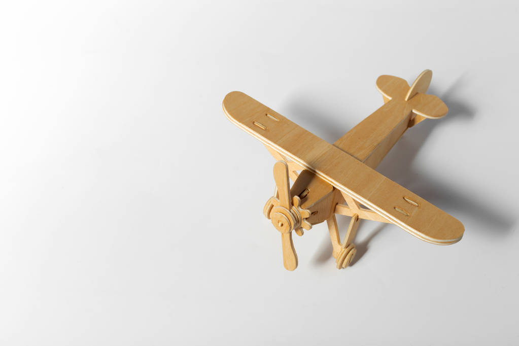 Nahaufnahme eines hölzernen Spielzeugflugzeugs isoliert auf hellem Hintergrund  - Foto, Bild