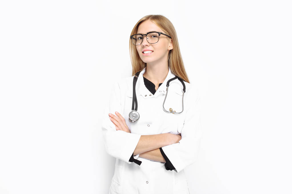 Молода дівчина в окулярах, зі стетоскопом навколо шиї, щасливо посміхається, на білому тлі. Концепція, лікарня, здоров'я
 - Фото, зображення