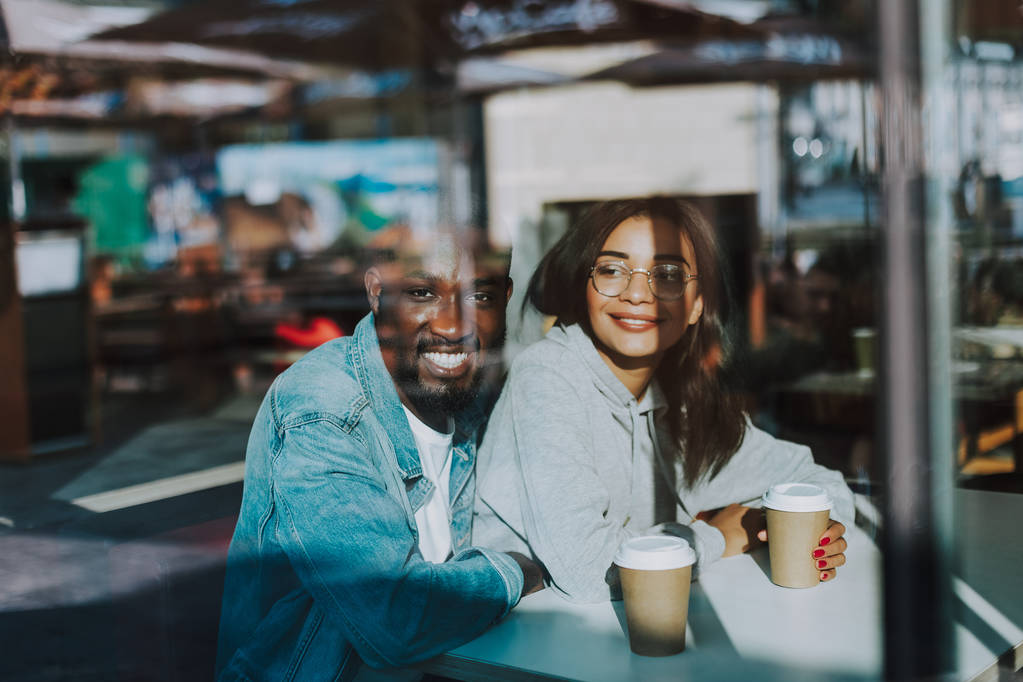 Happy man hugging his girlfriend while sitting in the cafe with her - Photo, Image