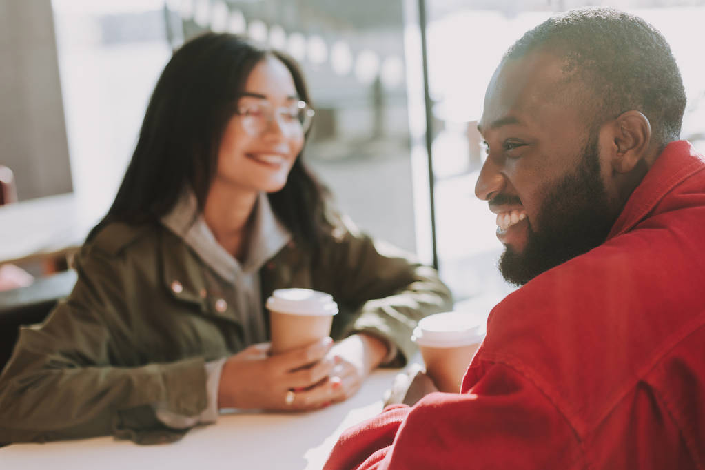 Positiivinen mies nauraa istuessaan tyttöystävänsä kanssa kahvilassa
 - Valokuva, kuva