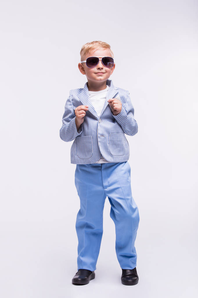 Szczęśliwy małego chłopca w okulary i stylowy Niebieski garnitur na białym tle na białym tle. Koncepcja moda dla dzieci - Zdjęcie, obraz