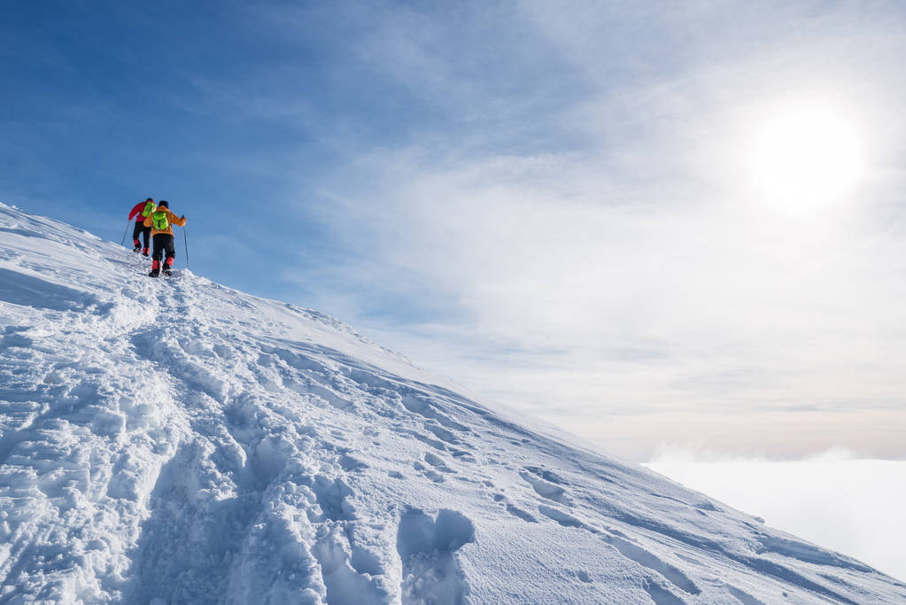 Toeristen op weg naar de besneeuwde bergtop. Winterwandelen. - Foto, afbeelding