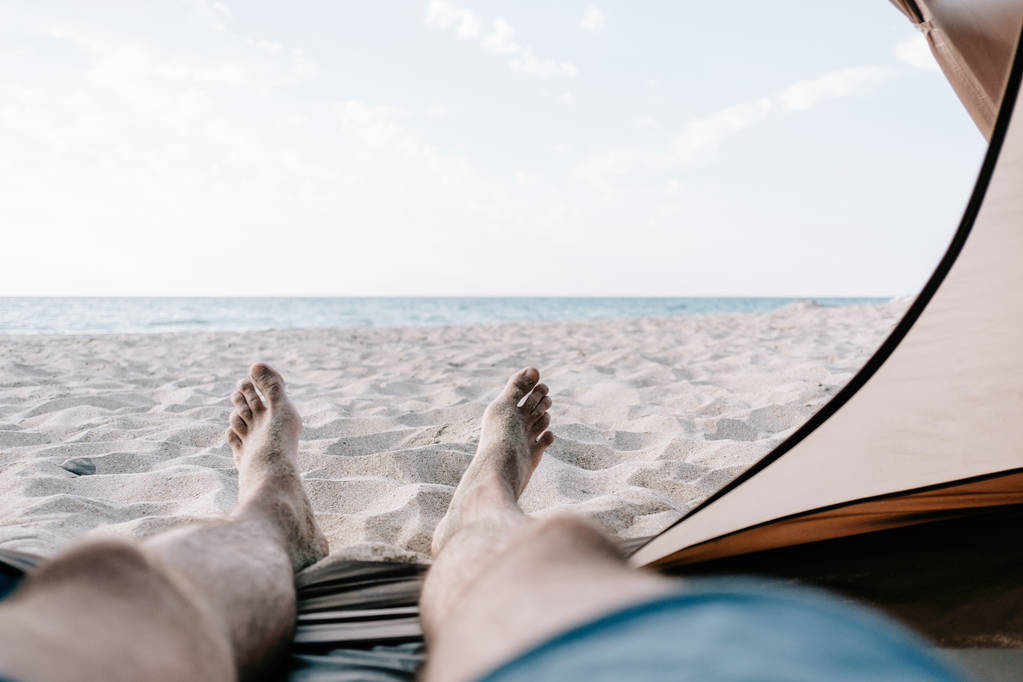 男は海、ビューのポイントの前に砂の海岸にテントでリラックス。ビーチ休暇. - 写真・画像