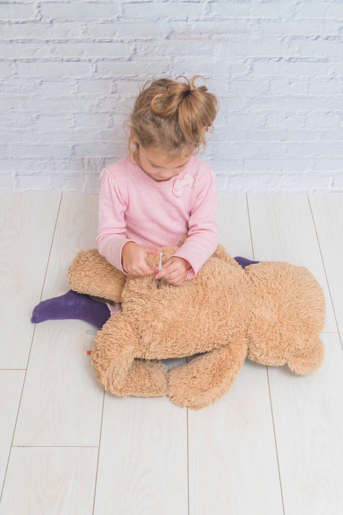 bambino, una ragazza fa un colpo per l'orso giocattolo, la siringa di insulina
 - Foto, immagini