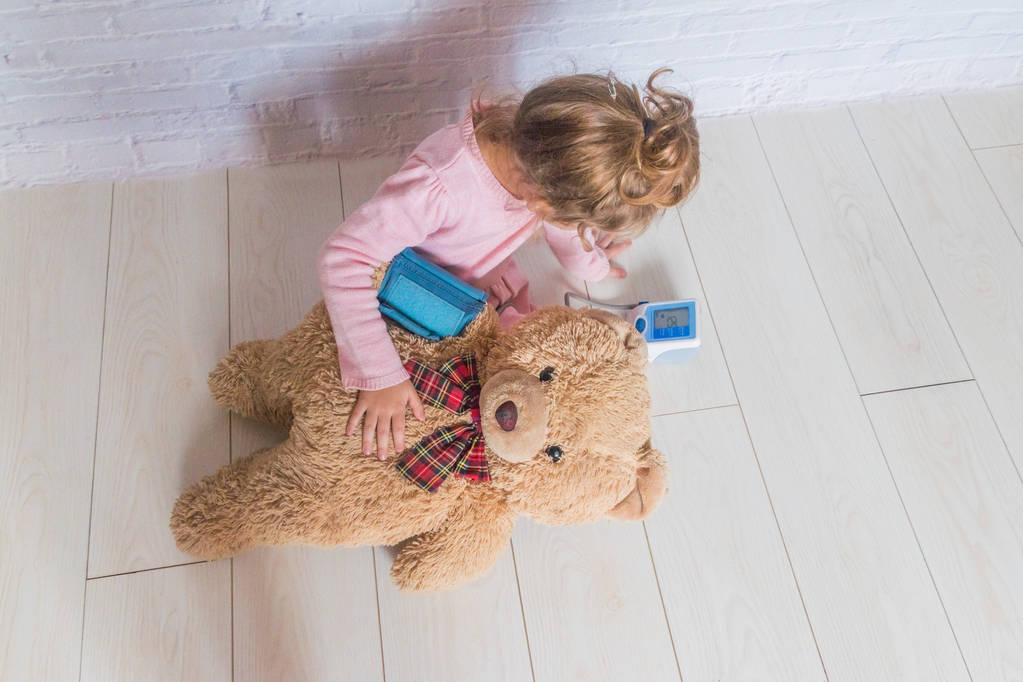 ragazza, un bambino che gioca medico, misura la pressione di un giocattolo orso
 - Foto, immagini