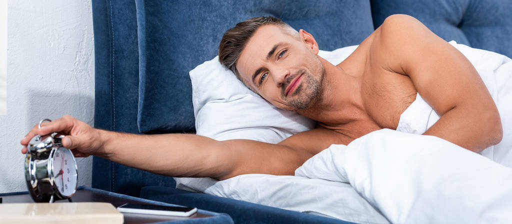 bell'uomo adulto che spegne la sveglia durante il mattino a casa
  - Foto, immagini