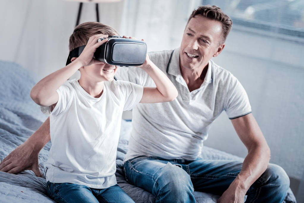 Kiinnostunut onnellinen poika istuu ja yllään VR lasit
. - Valokuva, kuva