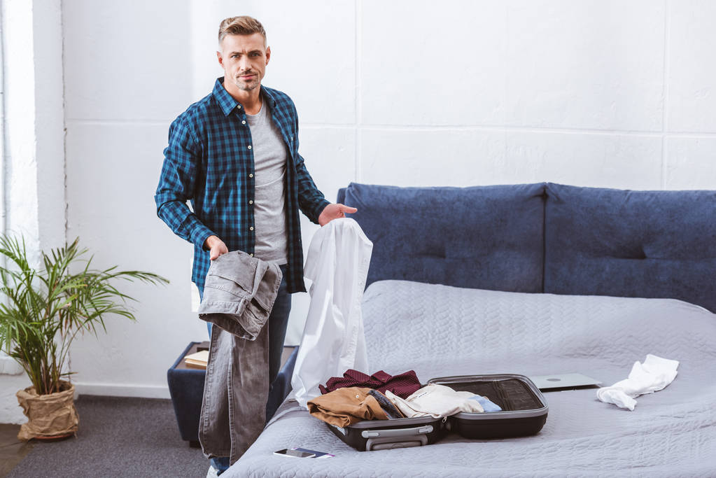 serio uomo imballaggio bagagli in camera da letto a casa
  - Foto, immagini