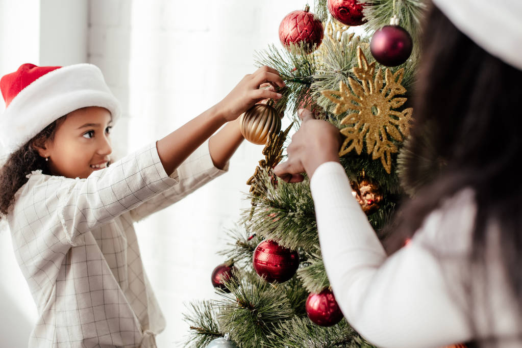 visão parcial da mulher afro-americana e criança decoração árvore de natal juntos em casa
 - Foto, Imagem