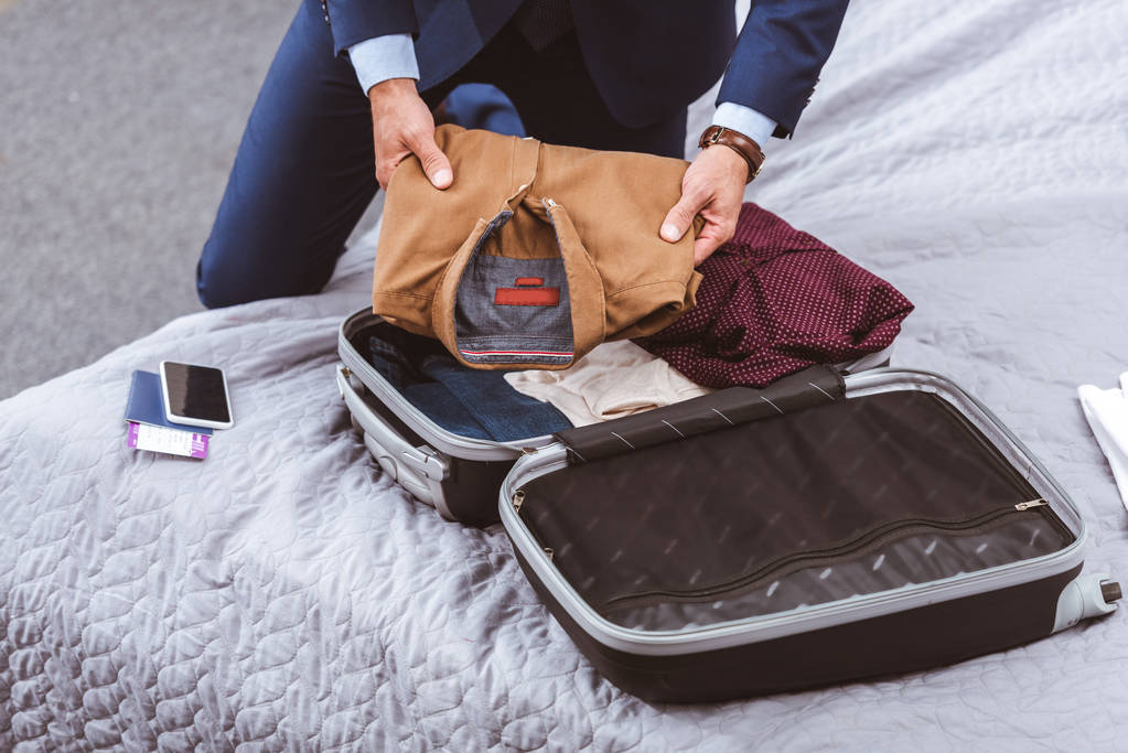 Oříznout záběr podnikatel v obleku cestovní kufřík na posteli  - Fotografie, Obrázek