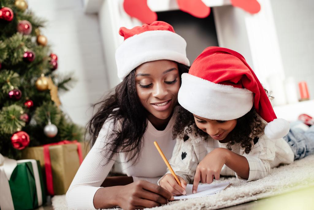 afro-americana madre aiutare figlia a scrivere lettera per Babbo Natale a casa
 - Foto, immagini