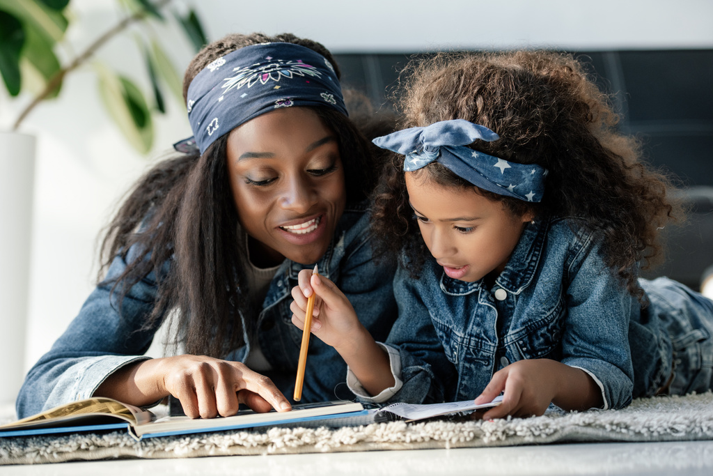 ritratto di donna afro-americana che aiuta la figlia a fare i compiti a casa
 - Foto, immagini