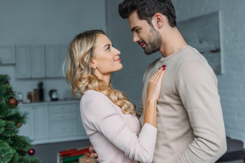 affectionate couple hugging in kitchen and looking at each other - Photo, Image
