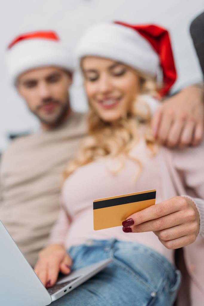 messa a fuoco selettiva di coppia in cappelli Santa shopping online con carta di credito e laptop a casa
 - Foto, immagini