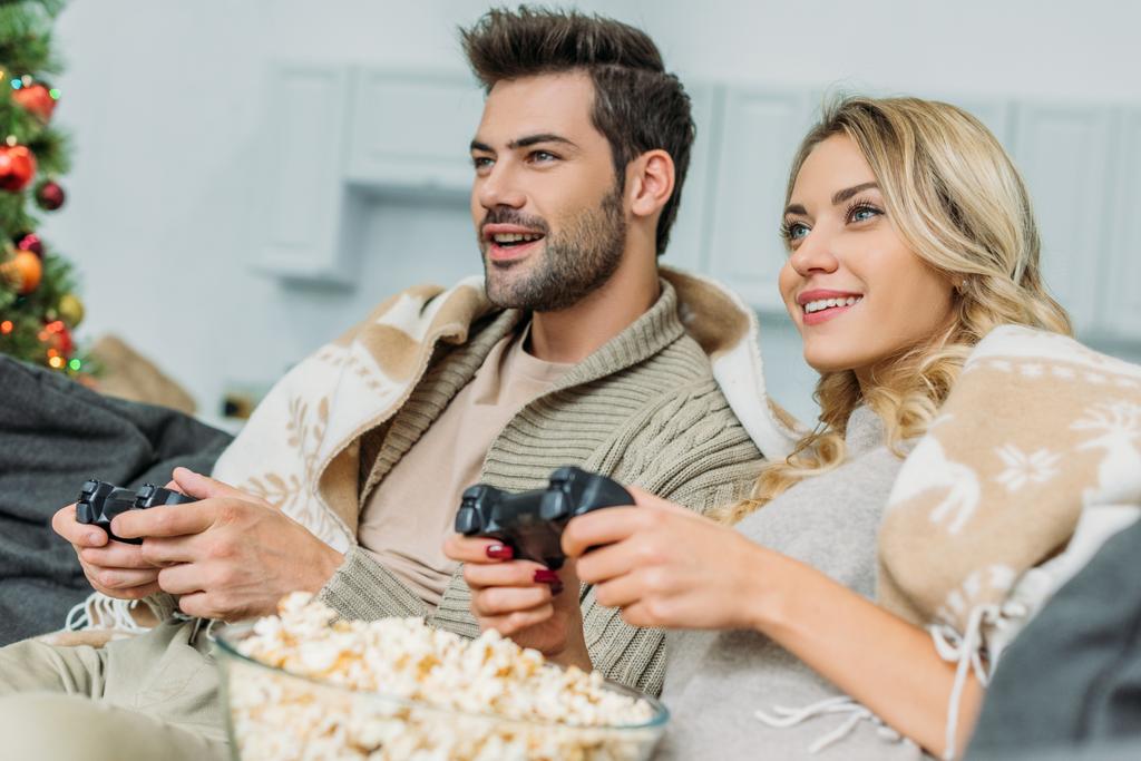 piękna Młoda para z popcornu, grając w gry wideo razem kanapie w domu - Zdjęcie, obraz