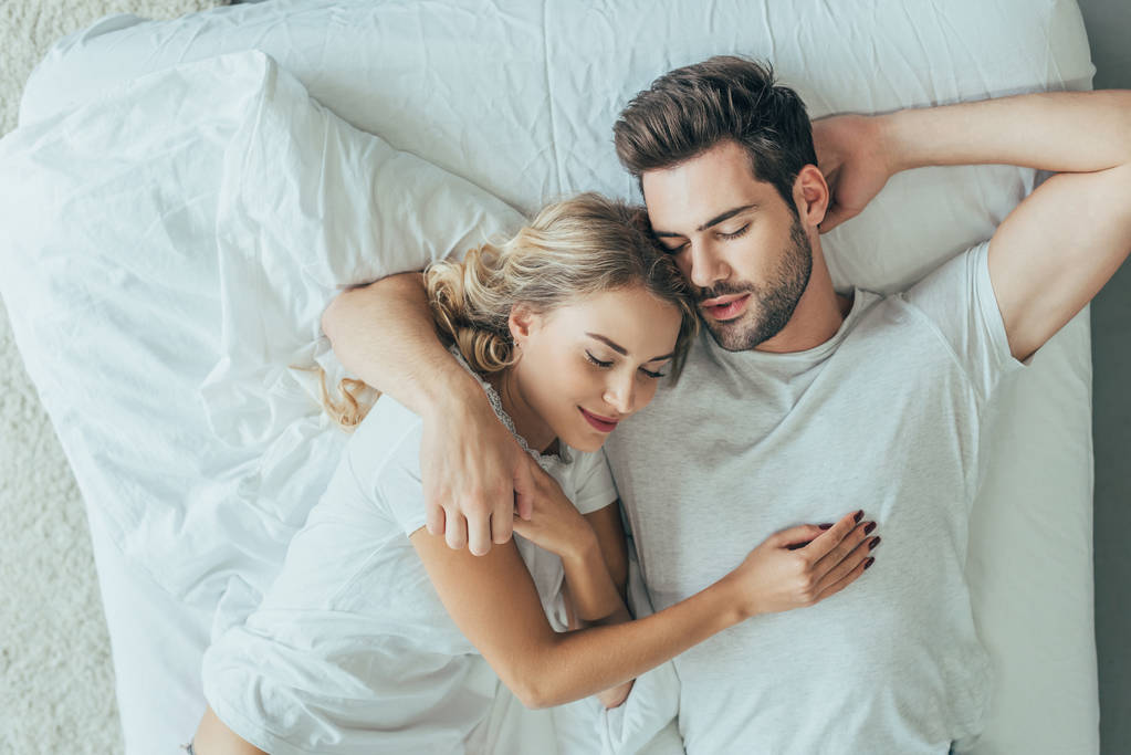 自宅のベッドで一緒に寝ている美しい若いカップルの平面図 - 写真・画像