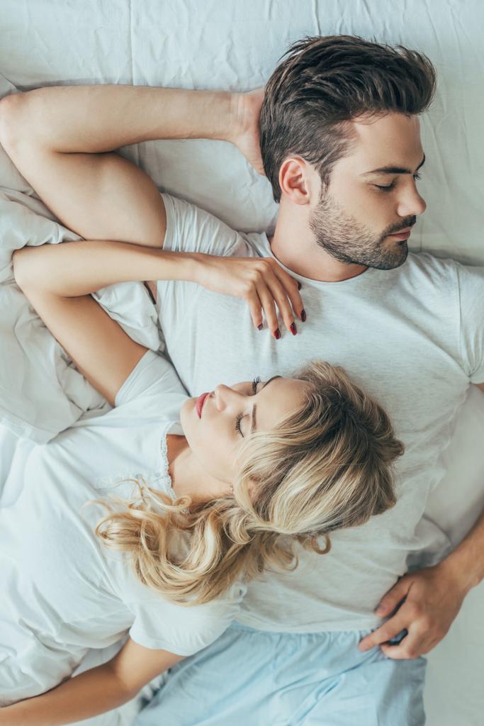 top view of beautiful young couple sleeping together in bed at home - Photo, Image
