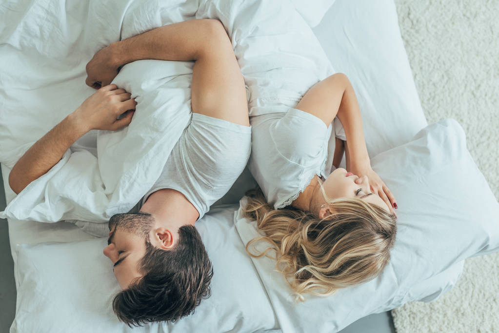 vista superior de la hermosa pareja joven durmiendo juntos espalda con espalda en la cama en casa
 - Foto, imagen