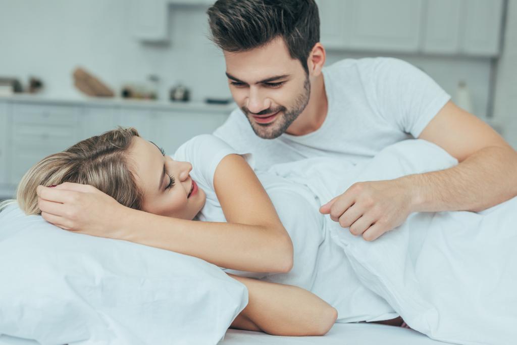 Gyönyörű fiatal pár ölelkezik otthon az ágyban. - Fotó, kép