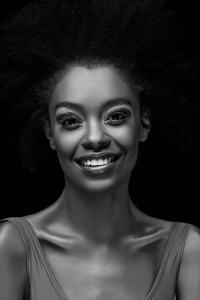 noir et blanc photo de femme afro-américaine souriante regardant la caméra isolée sur noir
 - Photo, image