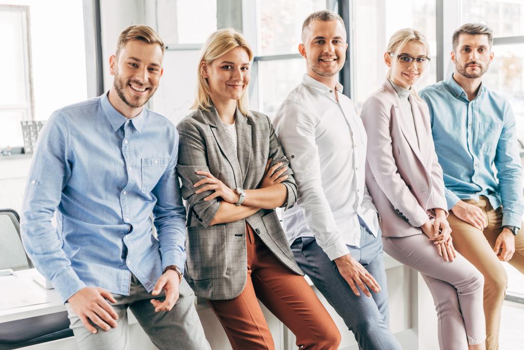 счастливая профессиональная молодая команда стартапов улыбается перед камерой в офисе
 - Фото, изображение