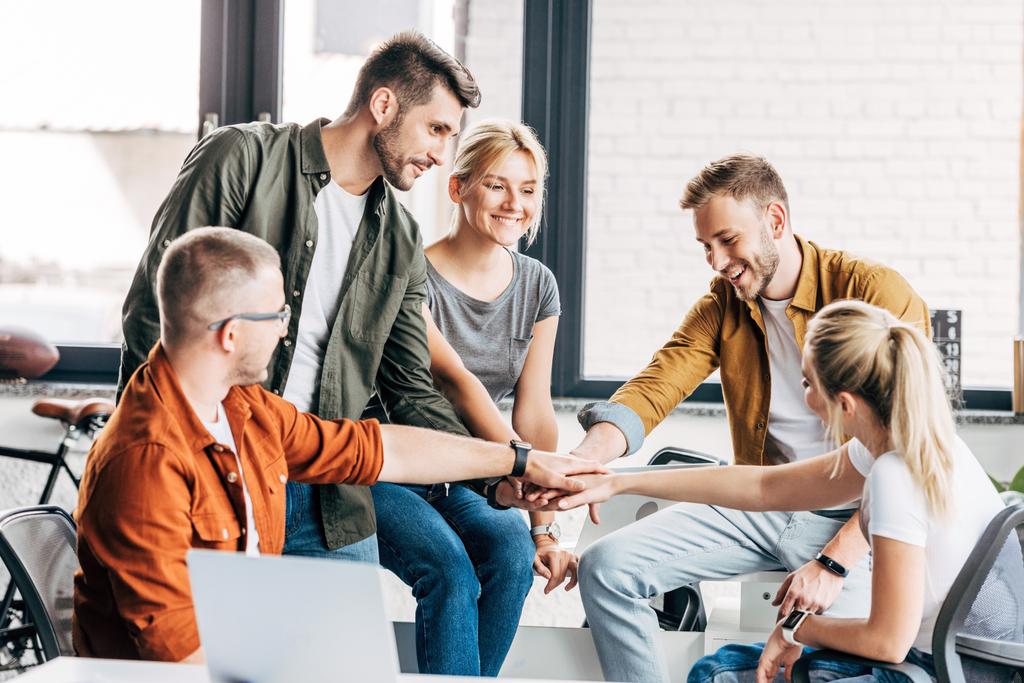 група щасливих молодих підприємців роблять жест команди під час роботи над стартапом разом в офісі
 - Фото, зображення