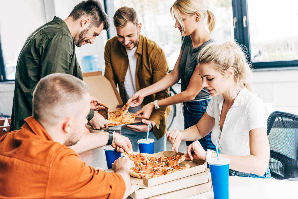 επιτυχημένες νέους επιχειρηματίες την πίτσα για το μεσημεριανό γεύμα μαζί ενώ εργαζόταν κατά την εκκίνηση στο γραφείο - Φωτογραφία, εικόνα