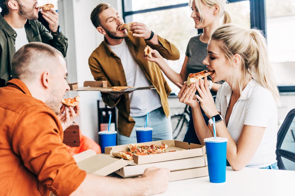 起動時にはオフィスで働いている間一緒に昼食にピザを食べて幸せな若い起業家のグループ - 写真・画像