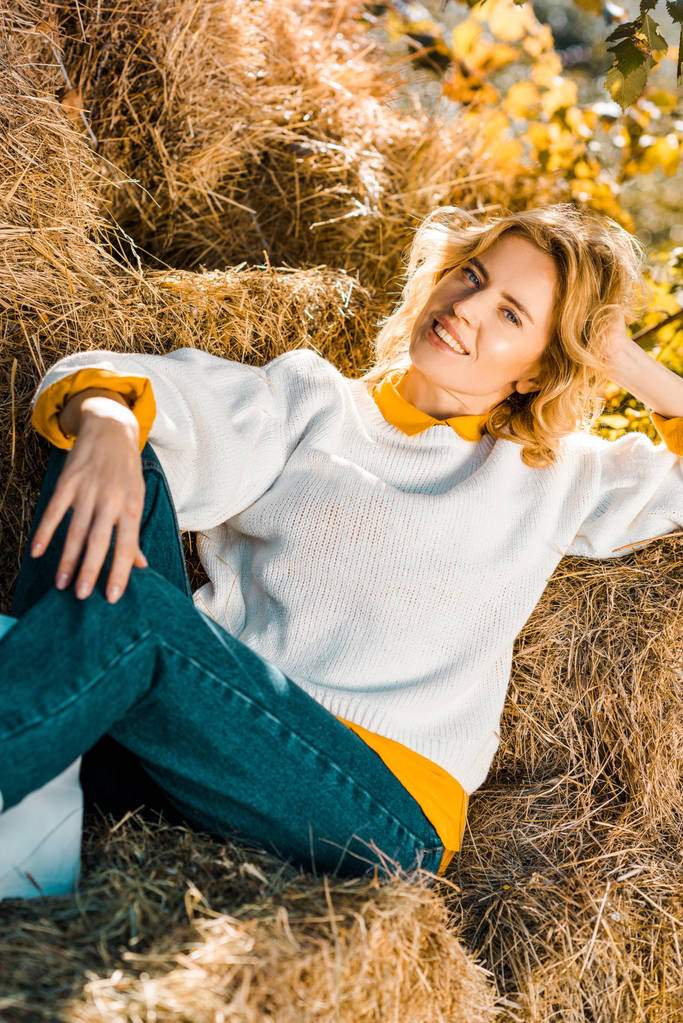 femme souriante regardant la caméra et s'allongeant sur des meules de foin au ranch
 - Photo, image