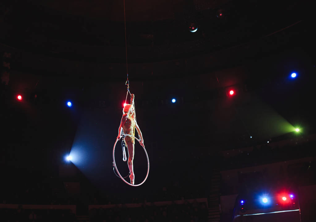 Aerial acrobat in the ring. A young girl performs the acrobatic elements in the air ring. - Photo, Image