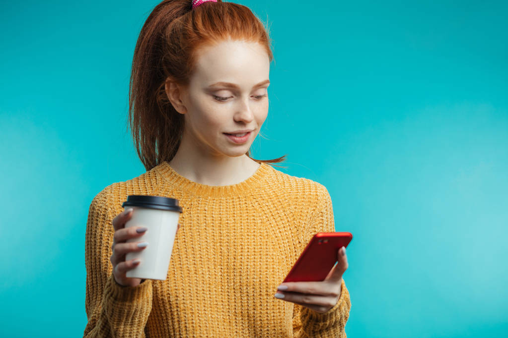 Giovane donna dai capelli rossi con caffè e smartphone isolato su b
 - Foto, immagini