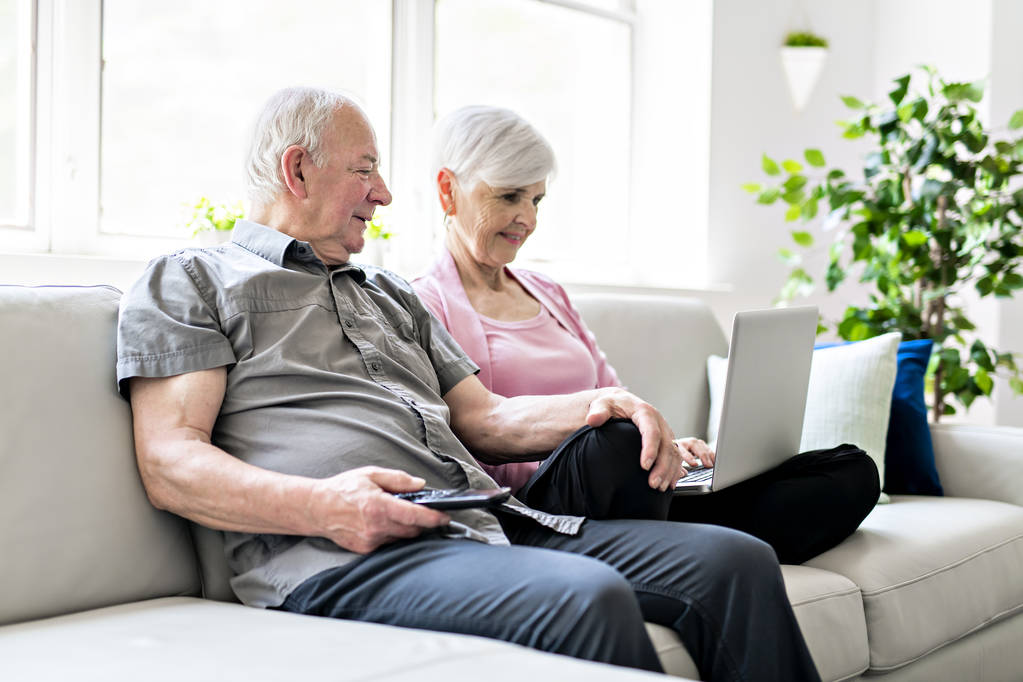 Una cariñosa y atractiva pareja de ancianos sentados juntos en un sofá
 - Foto, Imagen