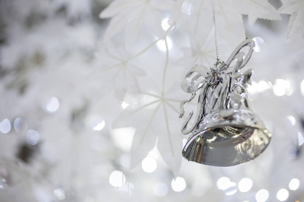 silberne Weihnachtsglockendekoration auf unscharf glitzerndem Feiertagshintergrund - Foto, Bild