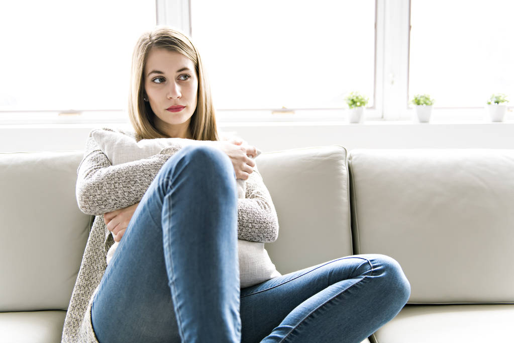 Przygnębiona młoda kobieta na kanapie w domu - Zdjęcie, obraz