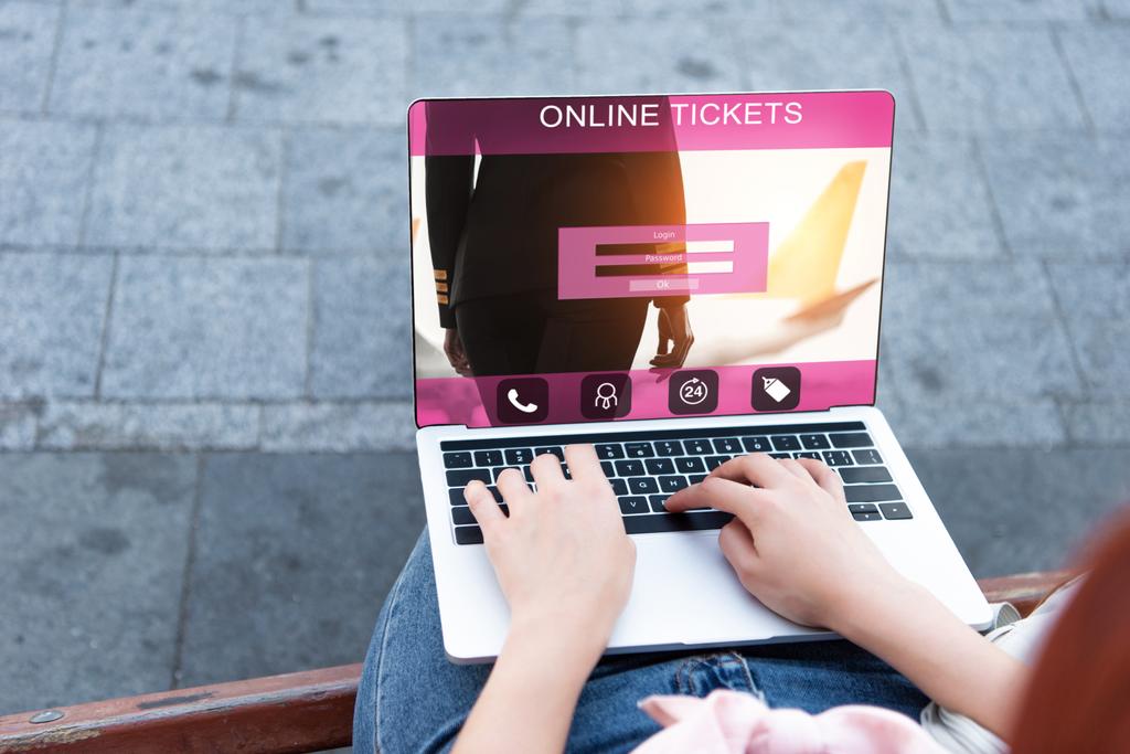 обрезанное изображение женщины, использующей ноутбук с устройством онлайн-билетов на улице
 - Фото, изображение