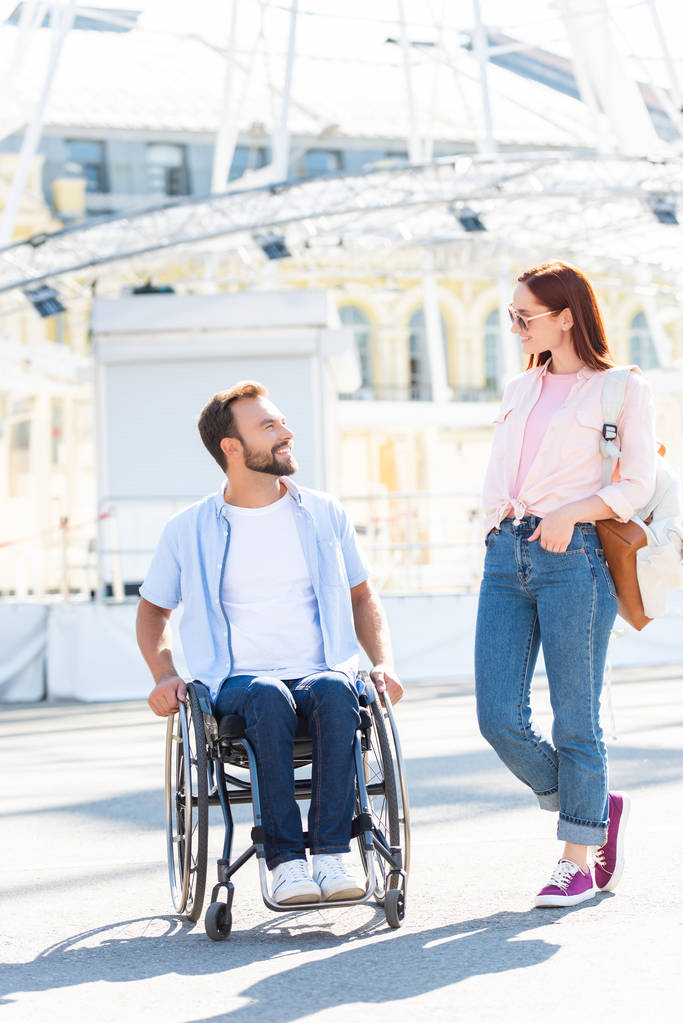 sourire beau petit ami en fauteuil roulant et petite amie qui se regardent dans la rue
 - Photo, image