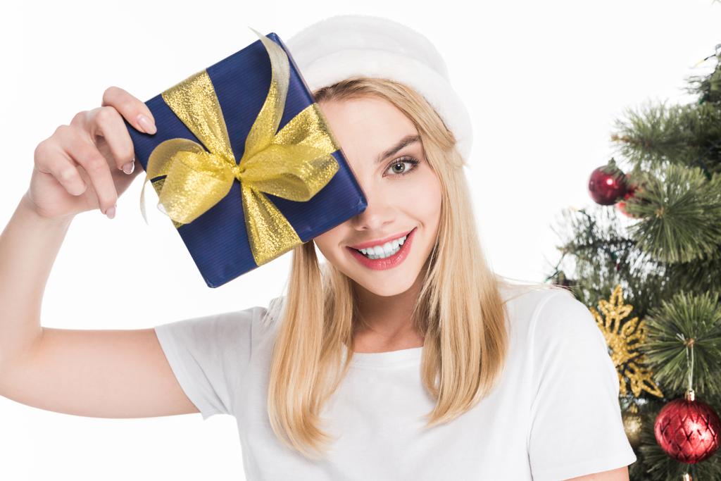 hymyilevä nainen joulupukki hattu tilalla kääritty lahja lähellä joulukuusi eristetty valkoinen
 - Valokuva, kuva