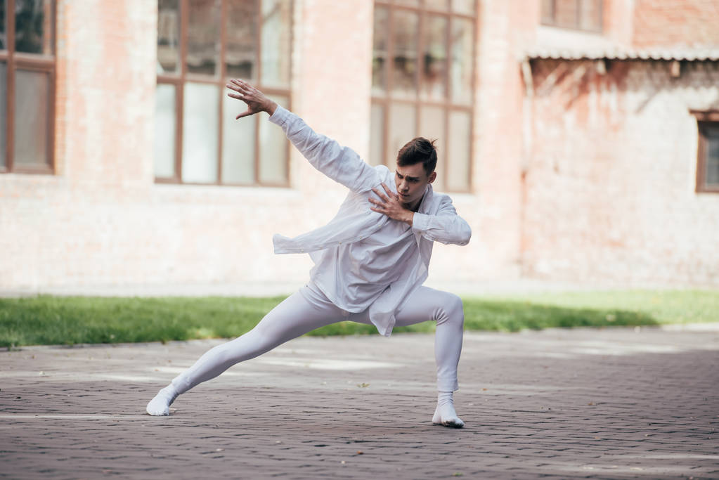 όμορφος νεαρός άνδρας χορευτής σε λευκά ρούχα χορού σε αστικό δρόμο της πόλης     - Φωτογραφία, εικόνα